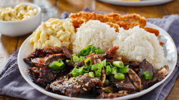 A plate with chicken katsu, korean kalbi beef short ribs, rice, and macaroni salad